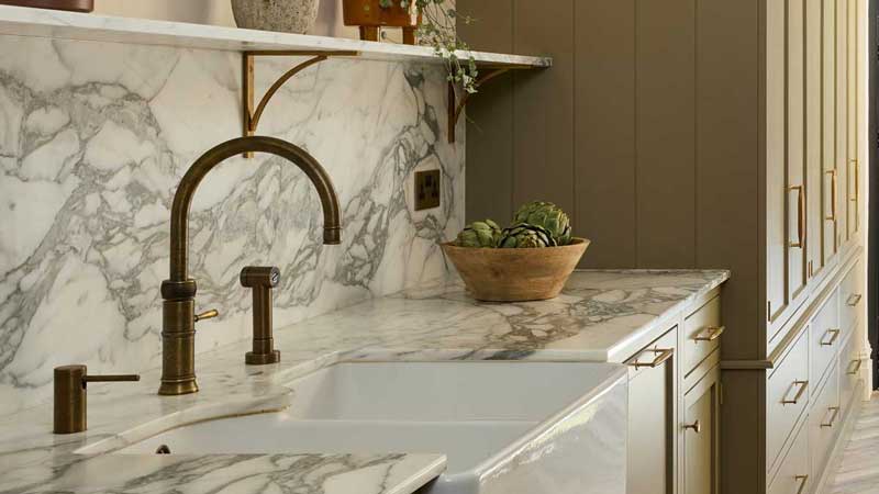 Stone worktop running continuously up into a full-height splashback in a Surrey kitchen